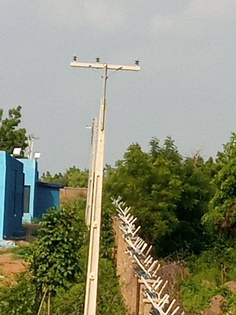 Newly erected concrete distribution pole with cross arm and three insulators against an open sky