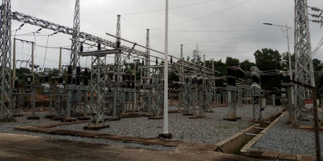 Outdoor substation switchyard with steel gantries, isolators, insulators and busbar structures on a gravel bed