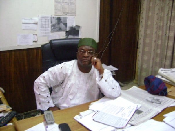 Historic photograph of Engr. Francis Okosobo-Ibe seated at his desk in an electricity utility management office